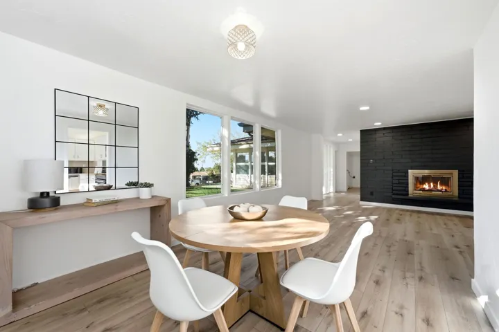 Open-concept living space with light wood-finish flooring, a black brick fireplace, and recessed lighting