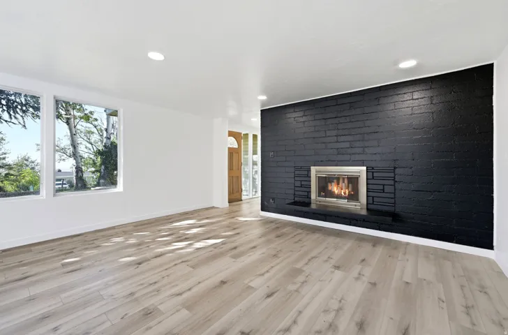 Wood-finish flooring throughout, featuring a black brick accent wall with a built-in fireplace