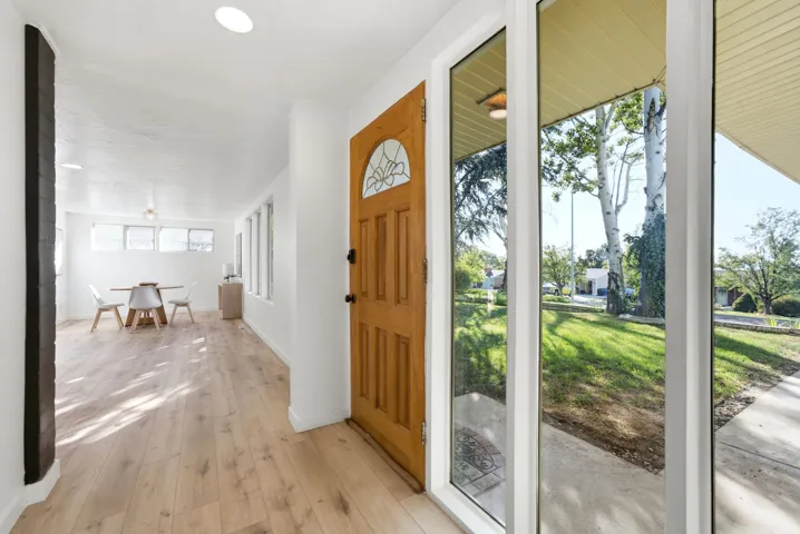 Wood-finish flooring throughout, recessed lighting, and a wood entry door with decorative glass