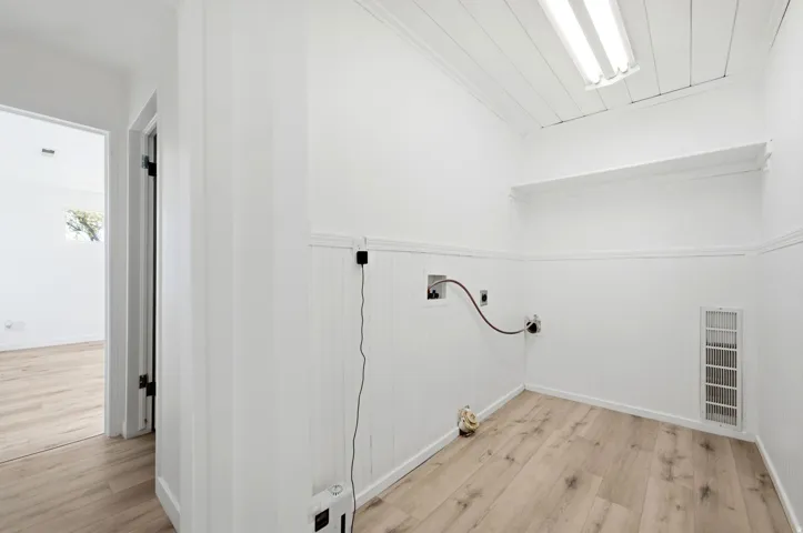 Utility space featuring wood-finish flooring, white paneled walls, and a recessed wall shelf