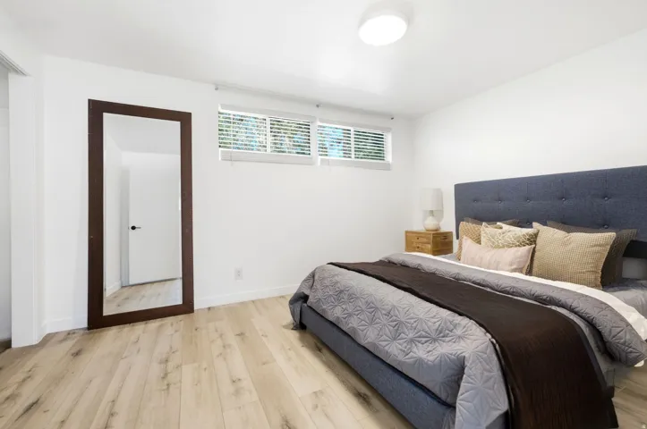 Light wood-finish flooring, recessed windows with blinds, and a flush-mount ceiling light