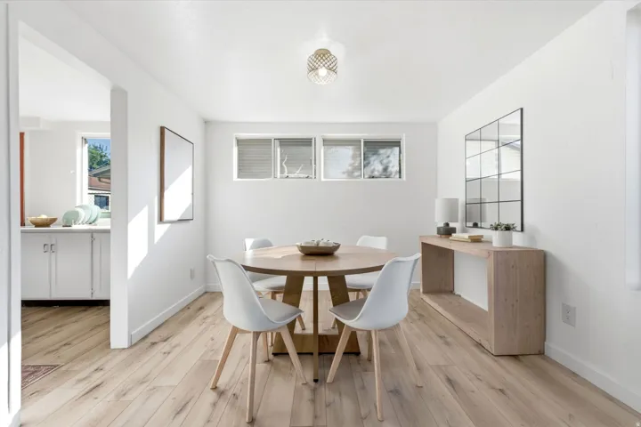 Bright dining area featuring a round wood-finish table, white modern chairs, and wood-finish flooring throughout