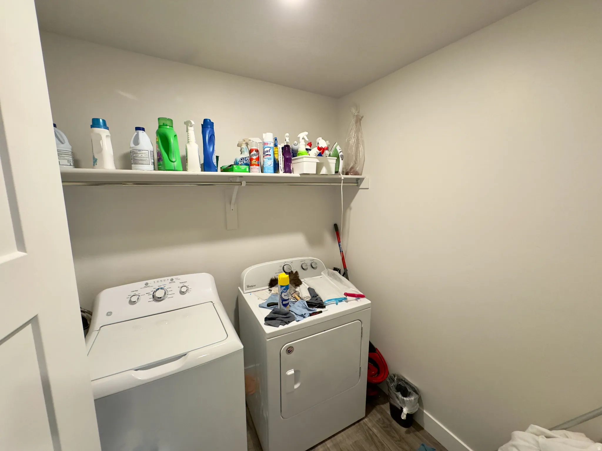 Dedicated laundry area featuring a wall-mounted shelf, light-toned walls, and wood-finish flooring
