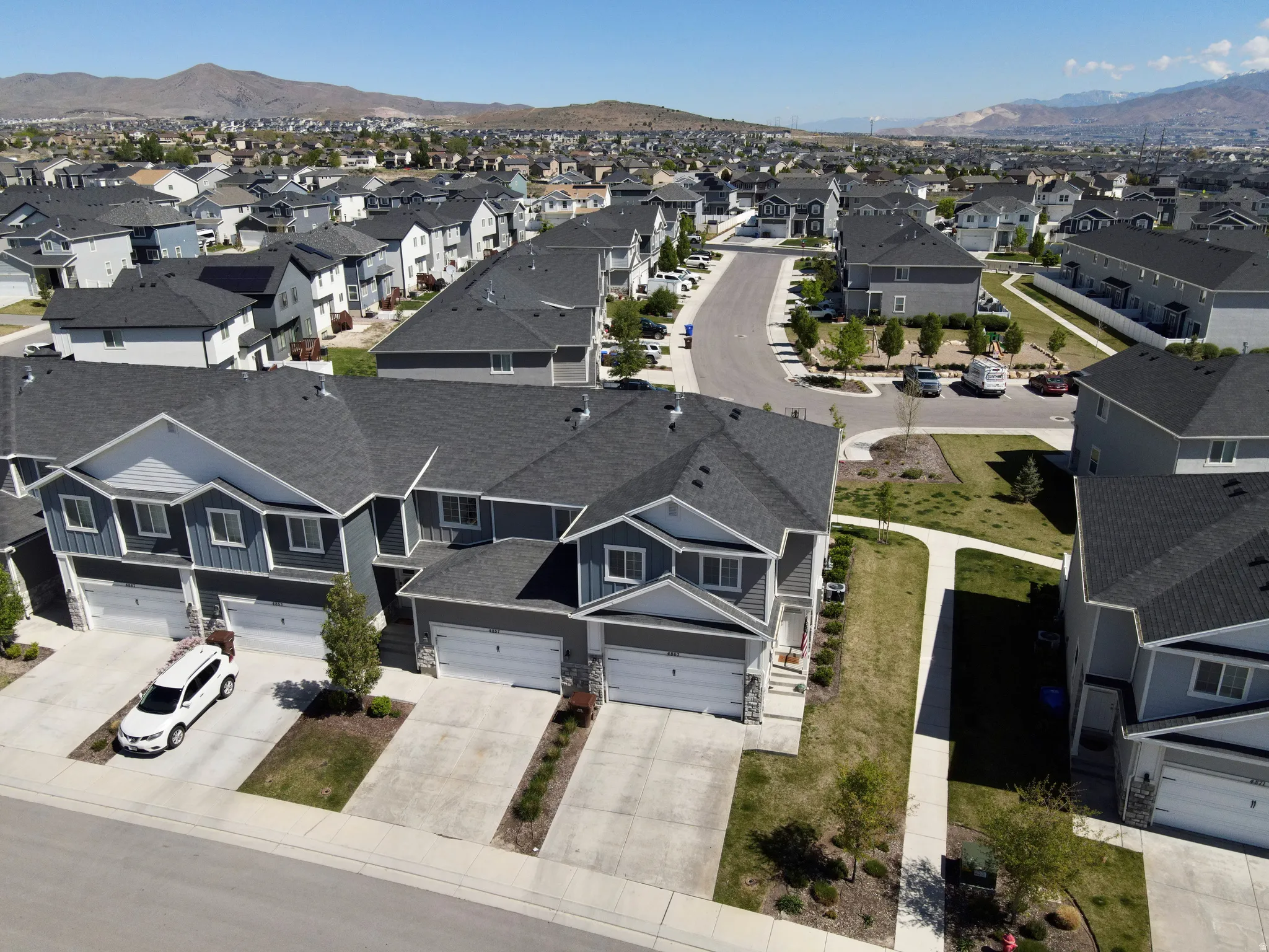 Townhome-style residences featuring dark gray siding, white trim, and attached garages