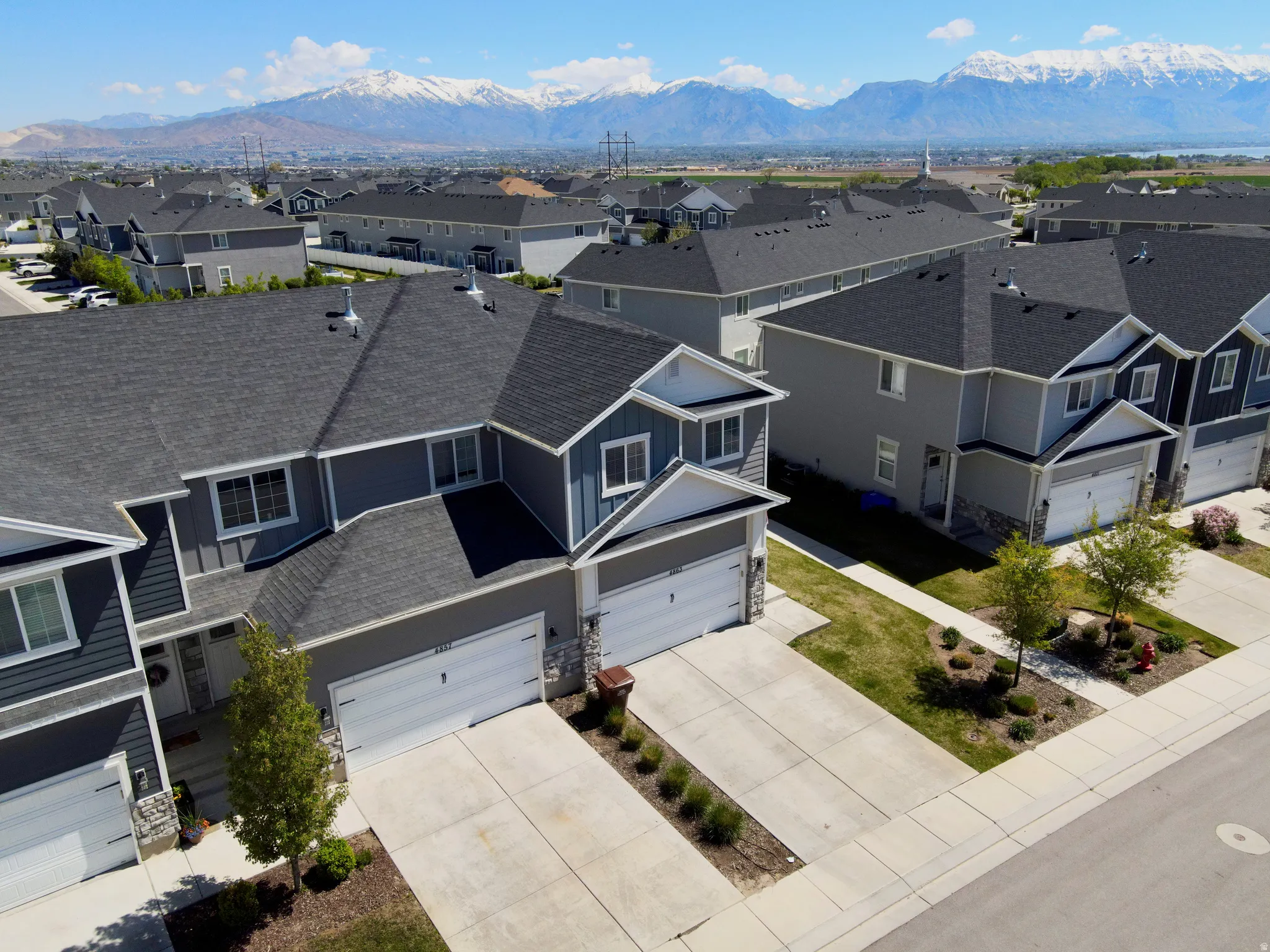 Contemporary residential community featuring multi-story homes with attached garages, concrete driveways, and manicured landscaping