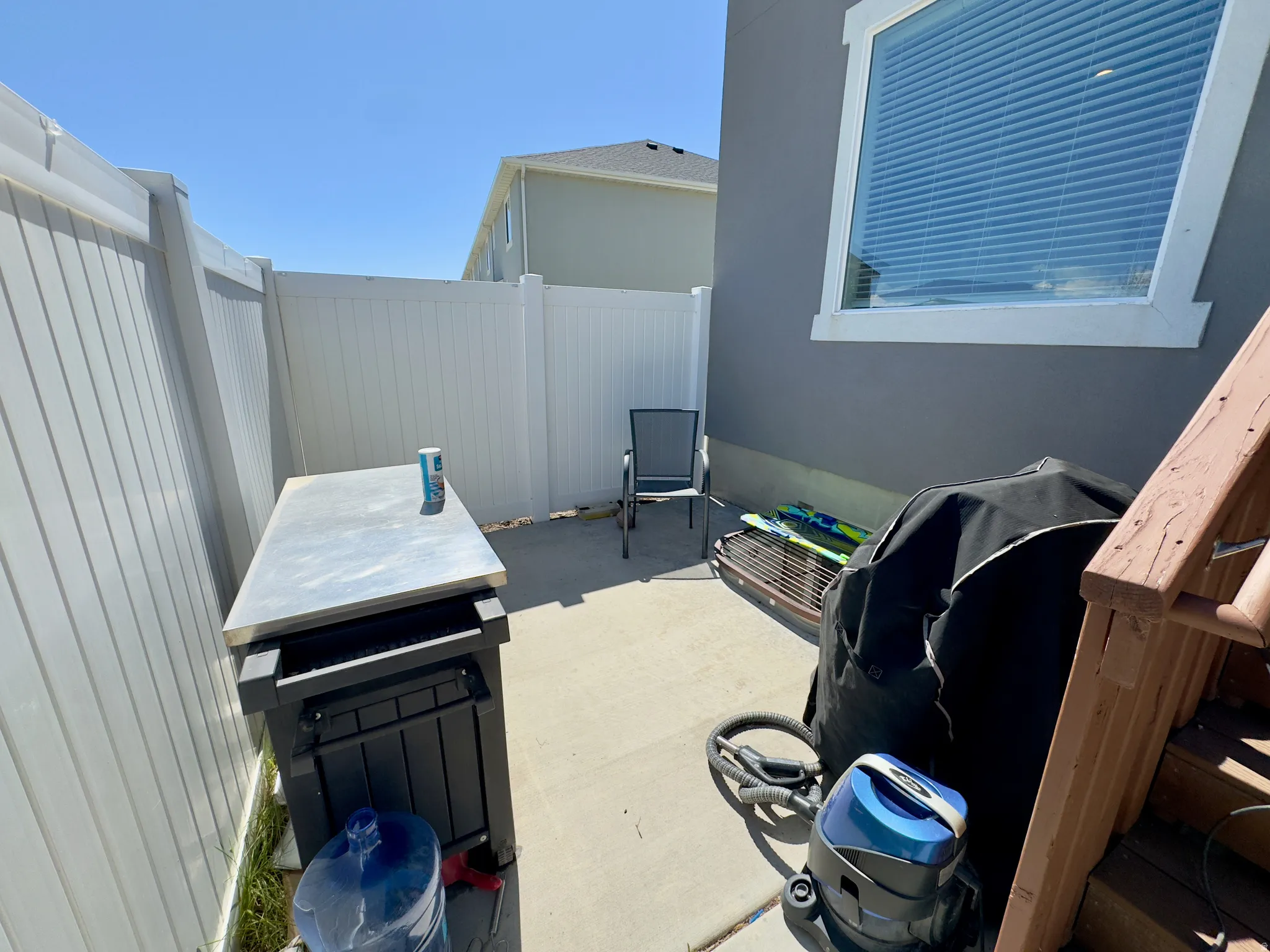 Concrete patio area enclosed by a white privacy fence