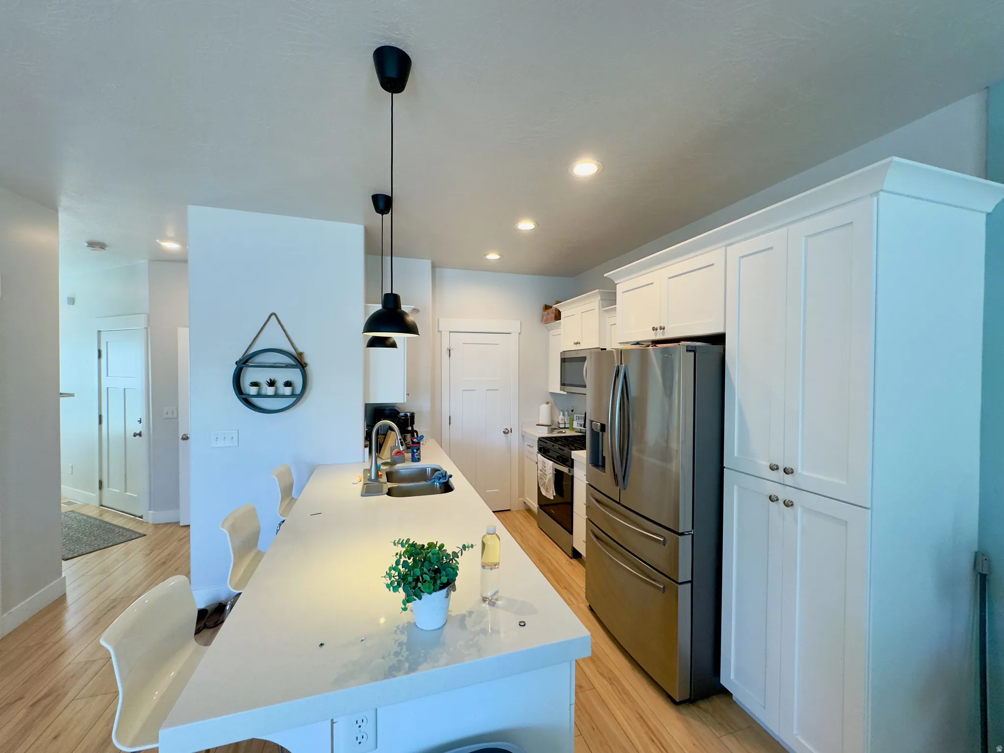 Kitchen featuring white shaker-style cabinetry, a stainless steel refrigerator, and wood-finish flooring