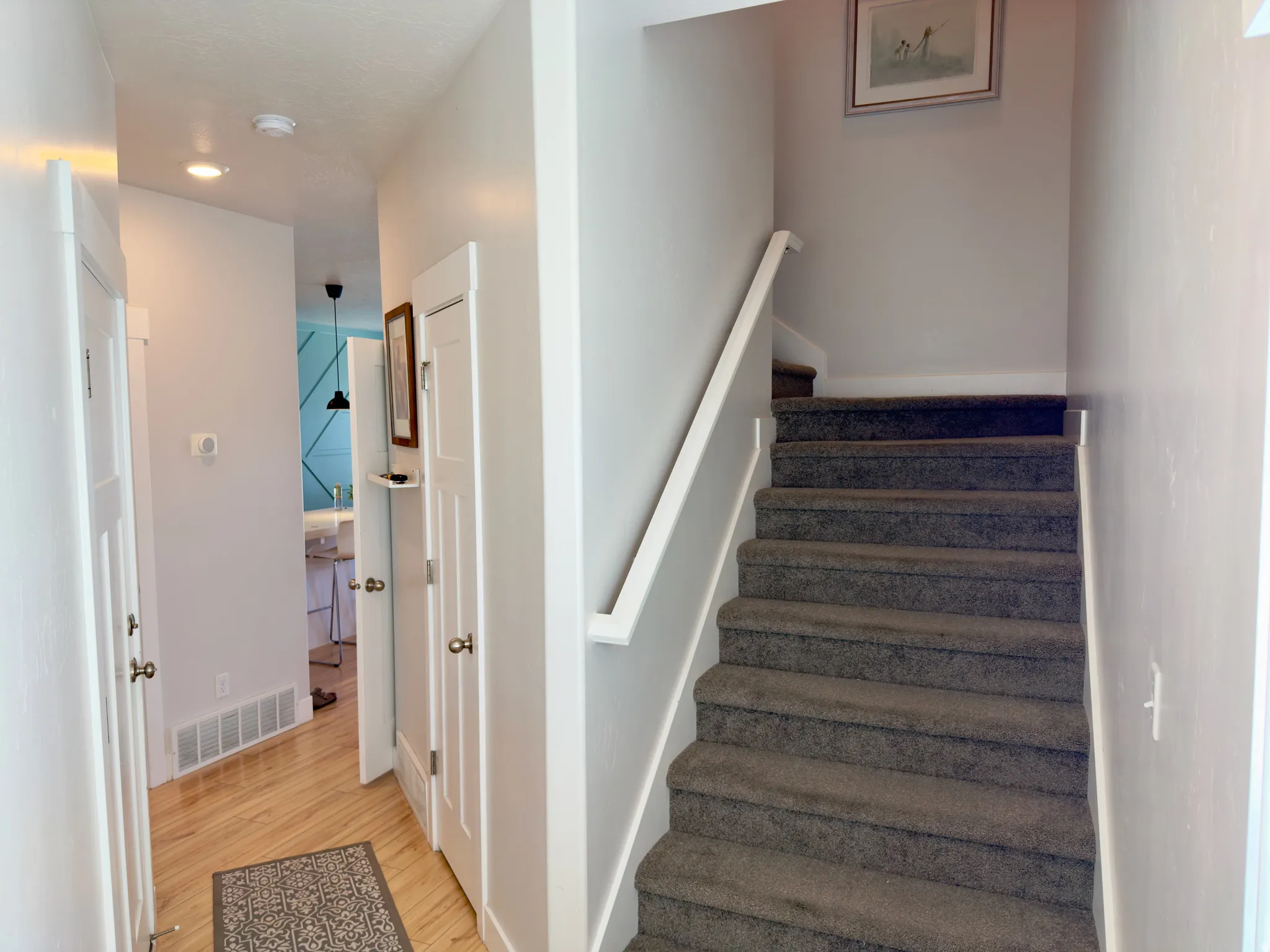 Carpeted staircase with white handrail and light gray walls
