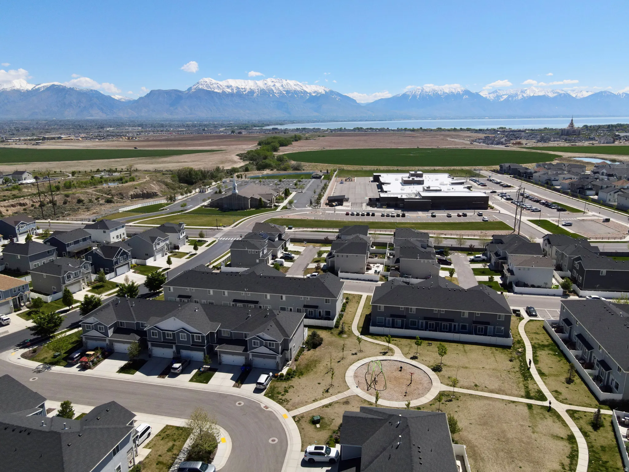 Aerial perspective showcasing a residential area with varied housing types, a prominent commercial building, and a community green space with a playground