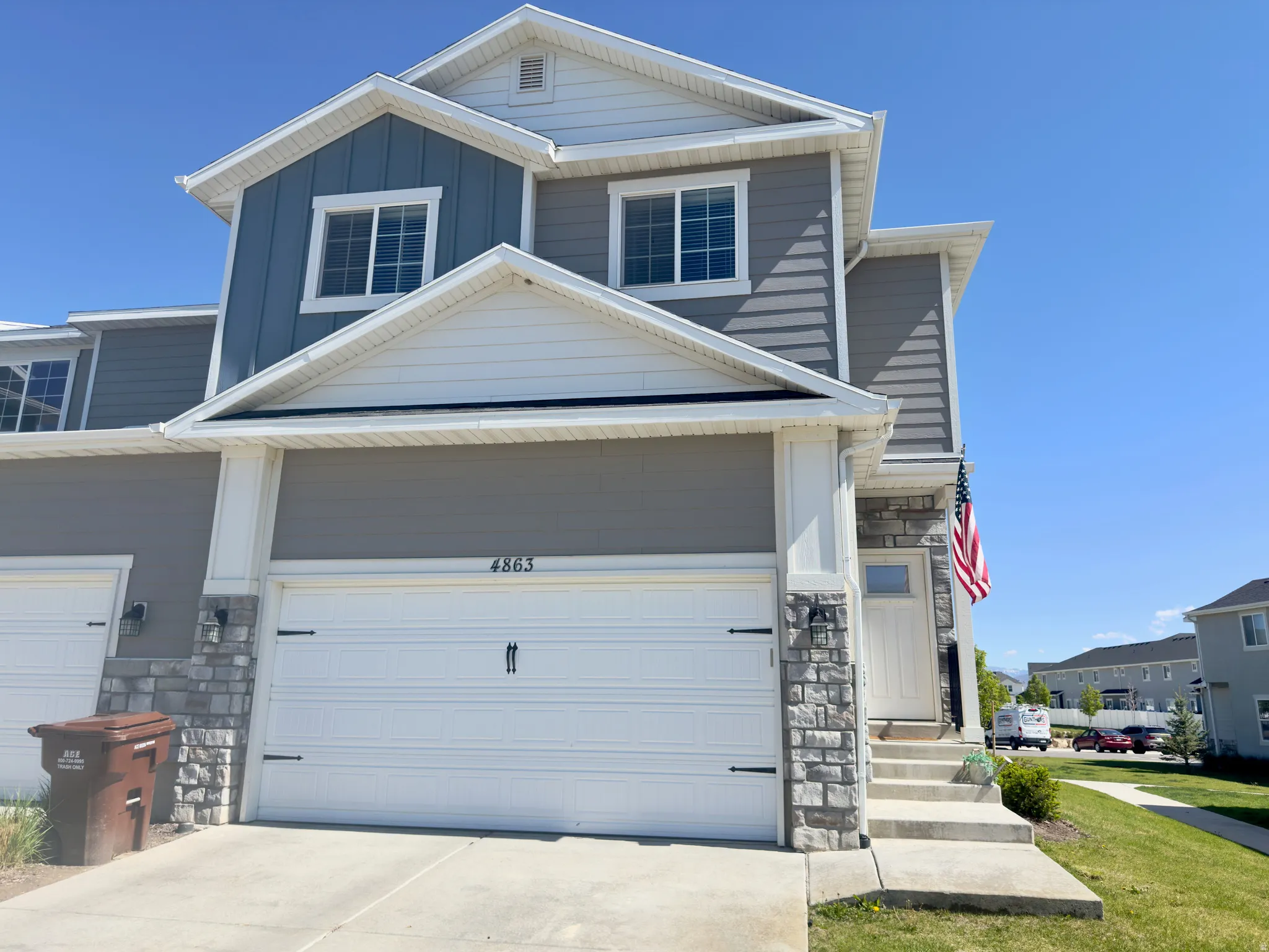 Two-story residential exterior featuring a light gray and blue siding combination with white trim