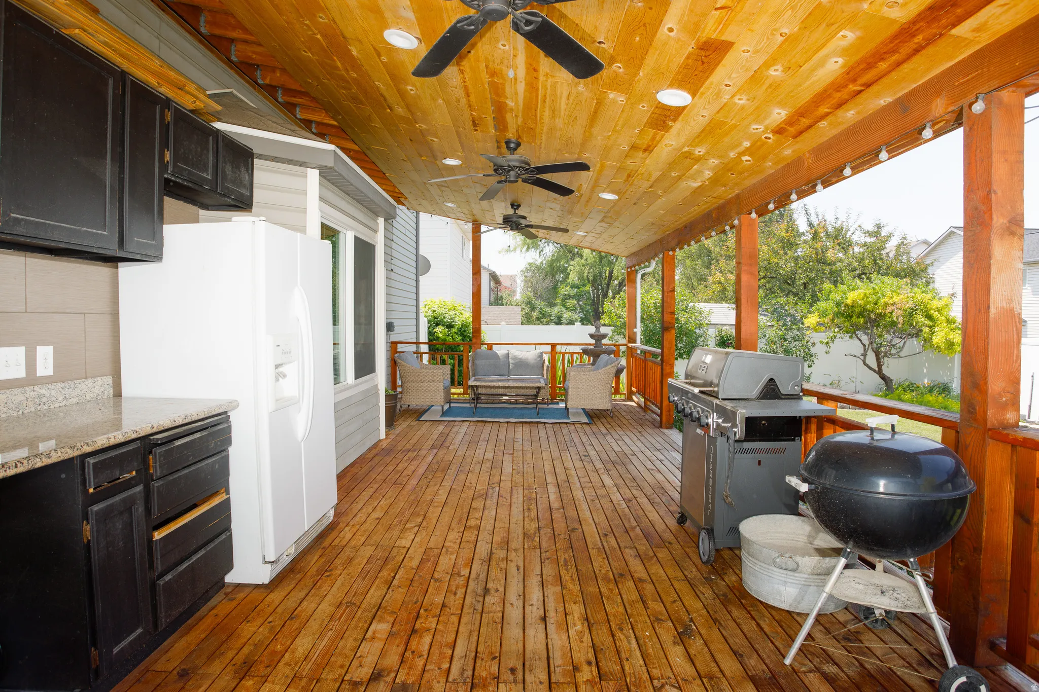 Expansive covered wood deck featuring a wood plank ceiling with recessed lighting and ceiling fans