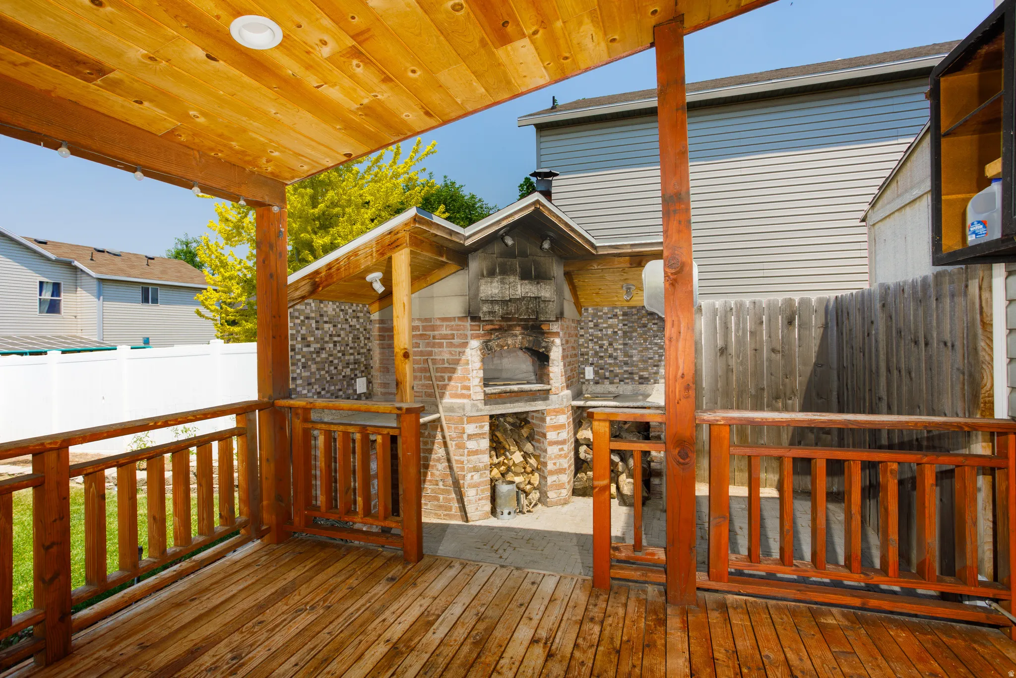 Expansive wood deck with a built-in outdoor kitchen featuring a brick-clad oven and a tiled backsplash