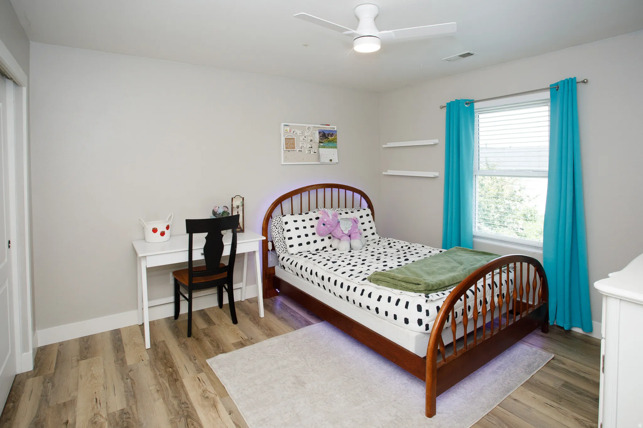 Bright room featuring wood-finish flooring, a white ceiling fan with integrated lighting, and a window with blinds