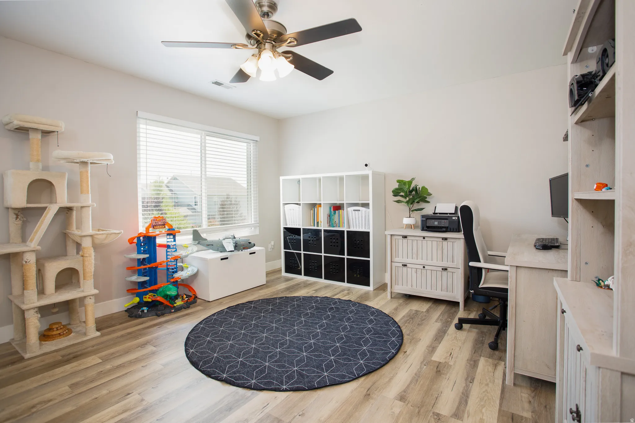 Bright room featuring wood-finish flooring and a ceiling fan with integrated lighting