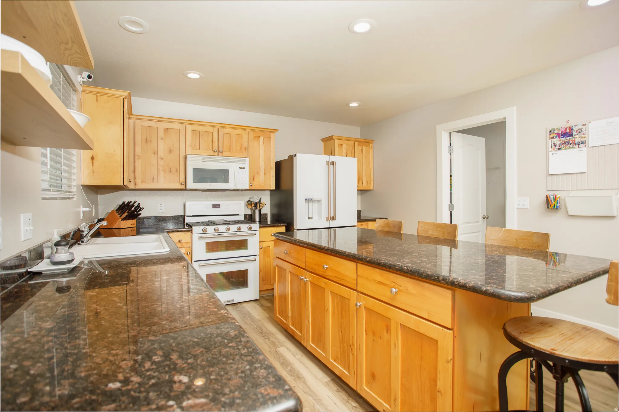 Kitchen featuring a central island with integrated seating, extensive countertop space, wood-finish cabinetry, and recessed lighting