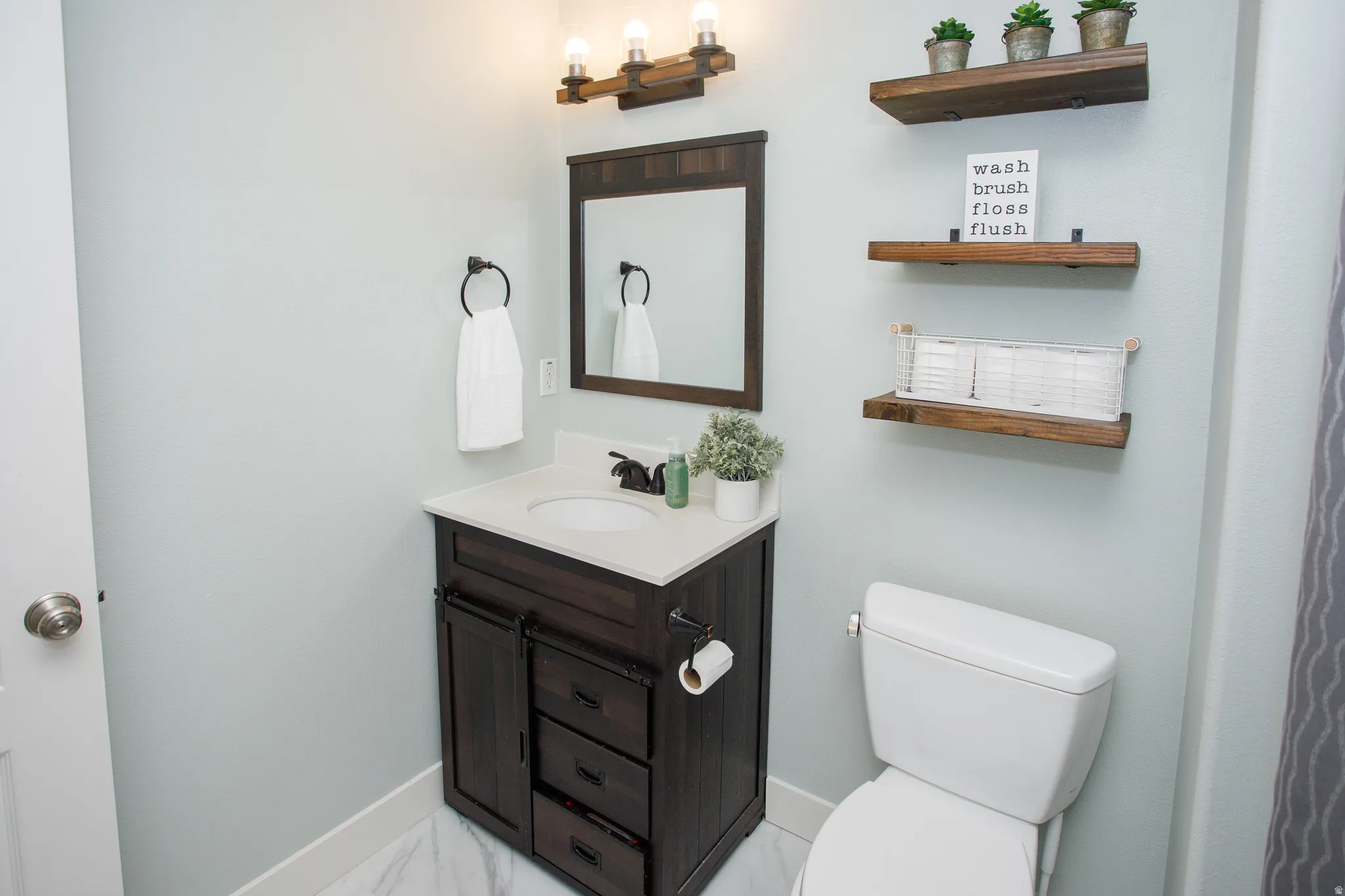 Bathroom featuring a dark wood-finish vanity with an integrated sink, a complementing dark wood-frame mirror, and a three-light fixture