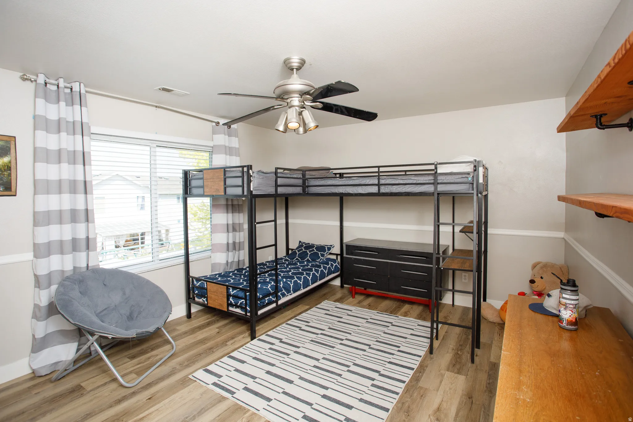 Room with wood-finish flooring, a ceiling fan, and a window with blinds