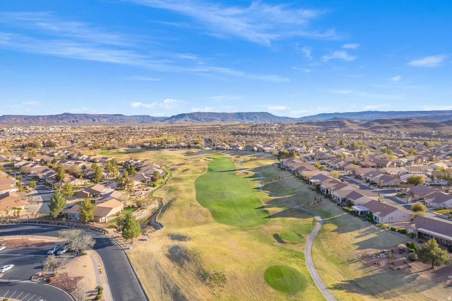 Expansive neighborhood with a golf course, residential properties, and distant mountains