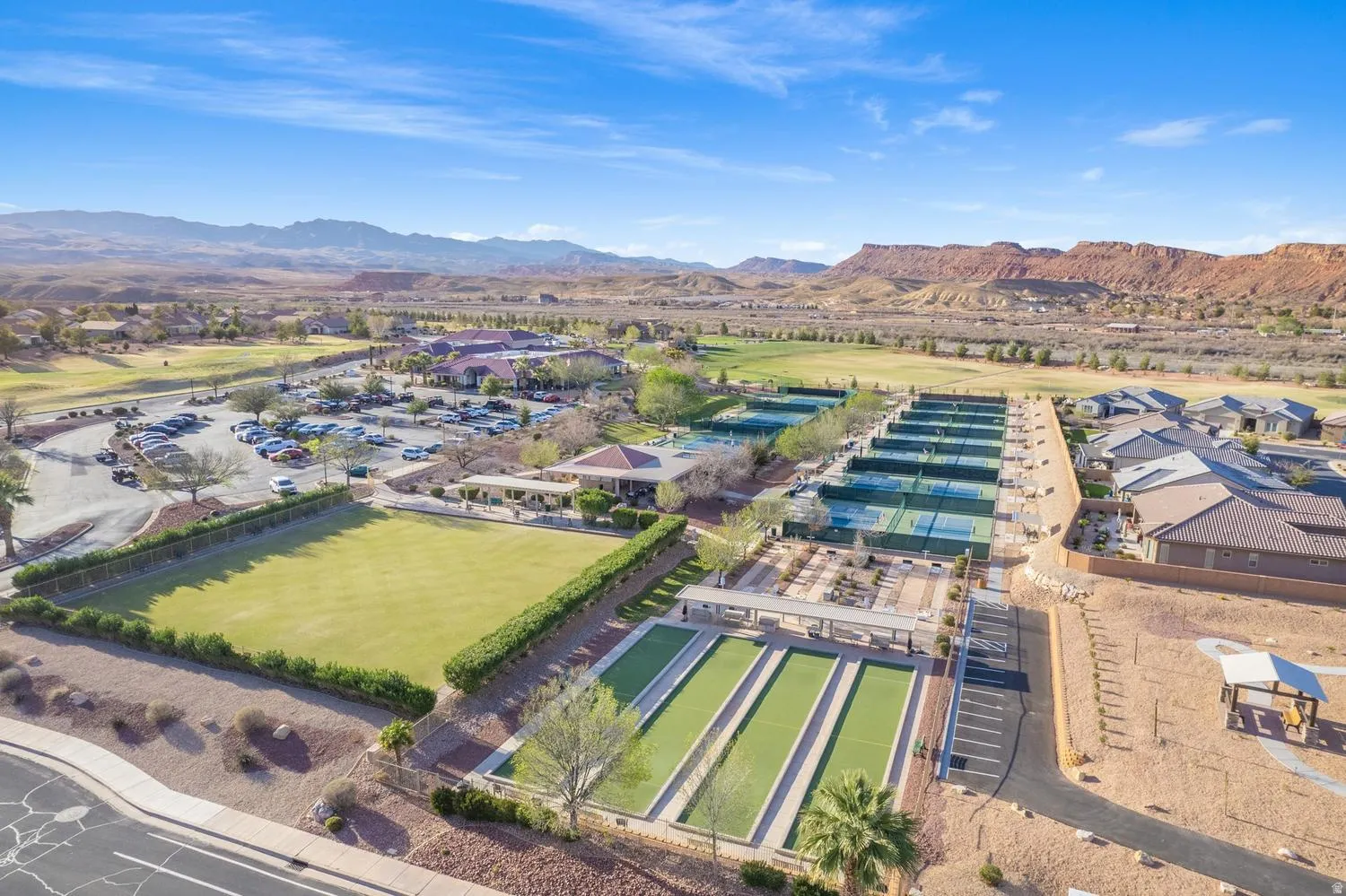 Expansive community amenities including multiple tennis courts, bocce ball courts, a large manicured lawn area, and a dedicated parking area