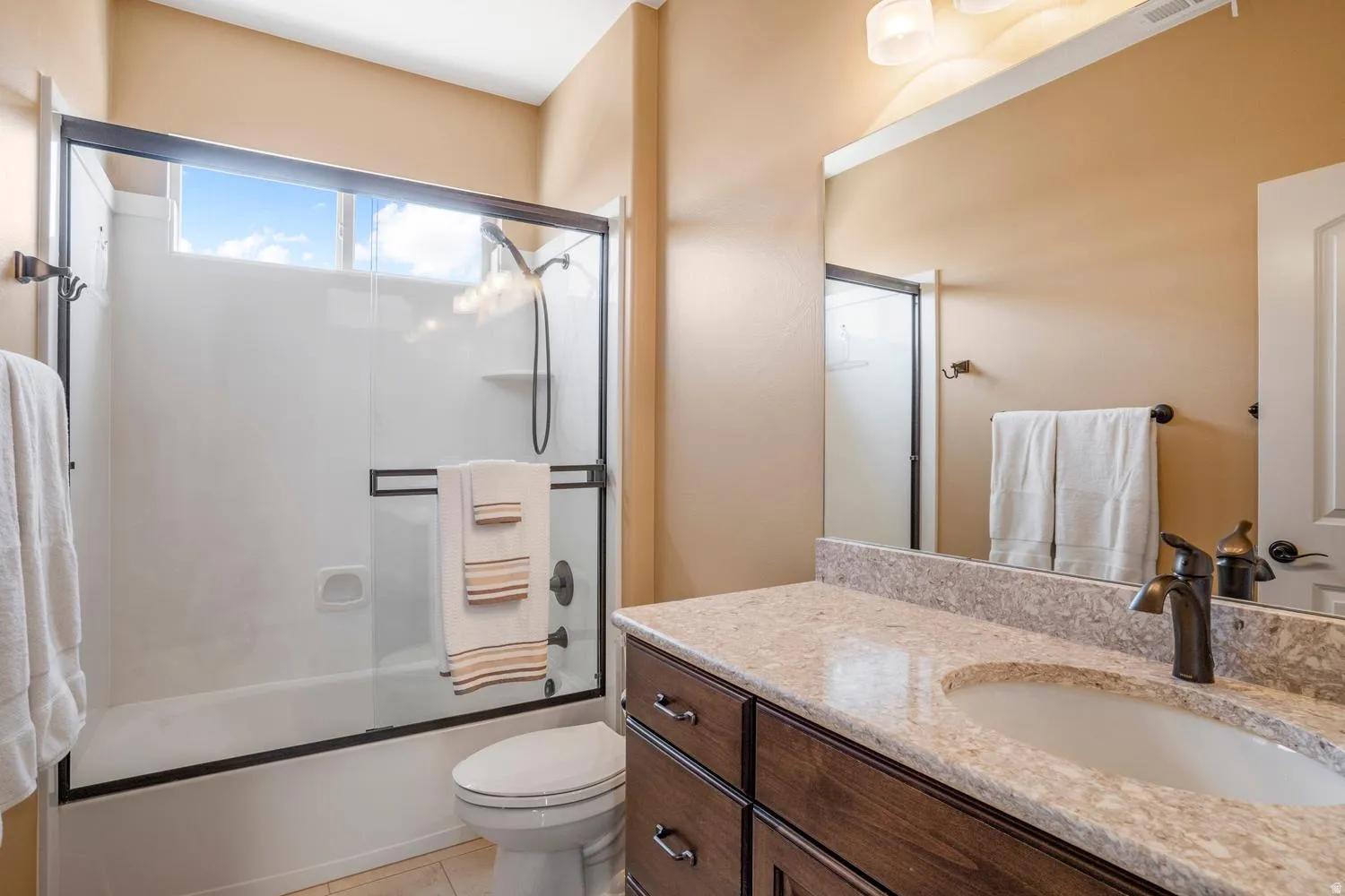 Bathroom featuring a single vanity with a light-colored countertop, an undermount sink, and a dark wood-finish cabinet