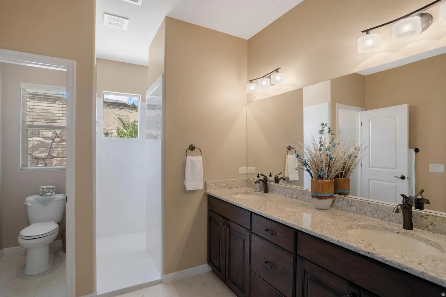 Dual vanity with granite-style countertop and dark wood-finish cabinetry