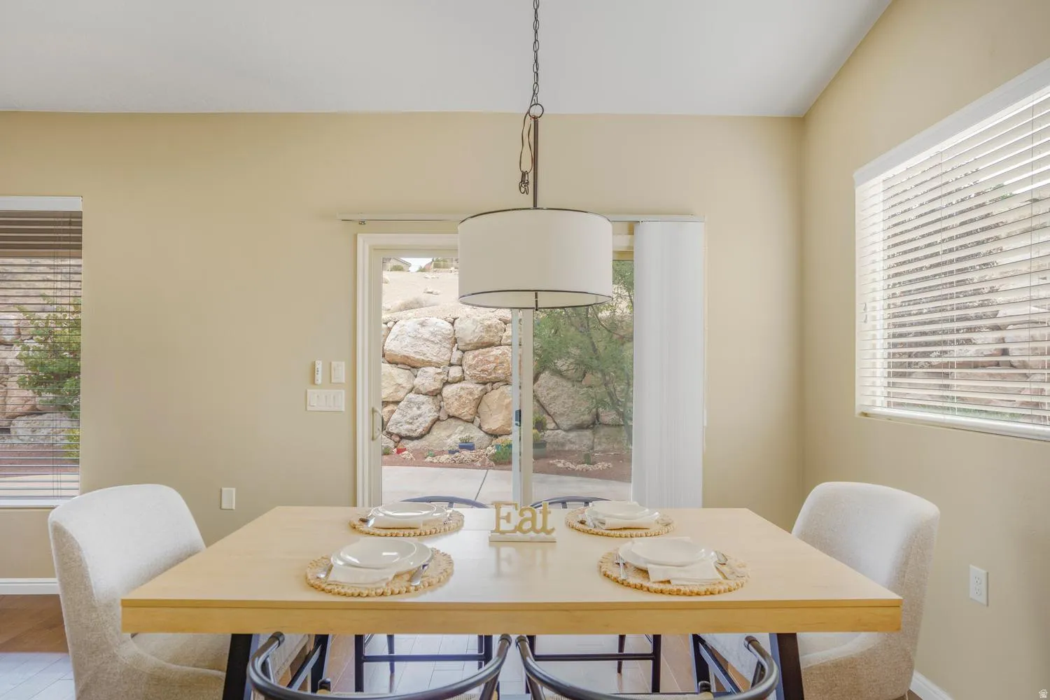Dining area with a drum pendant light, light-toned walls, and a sliding glass door