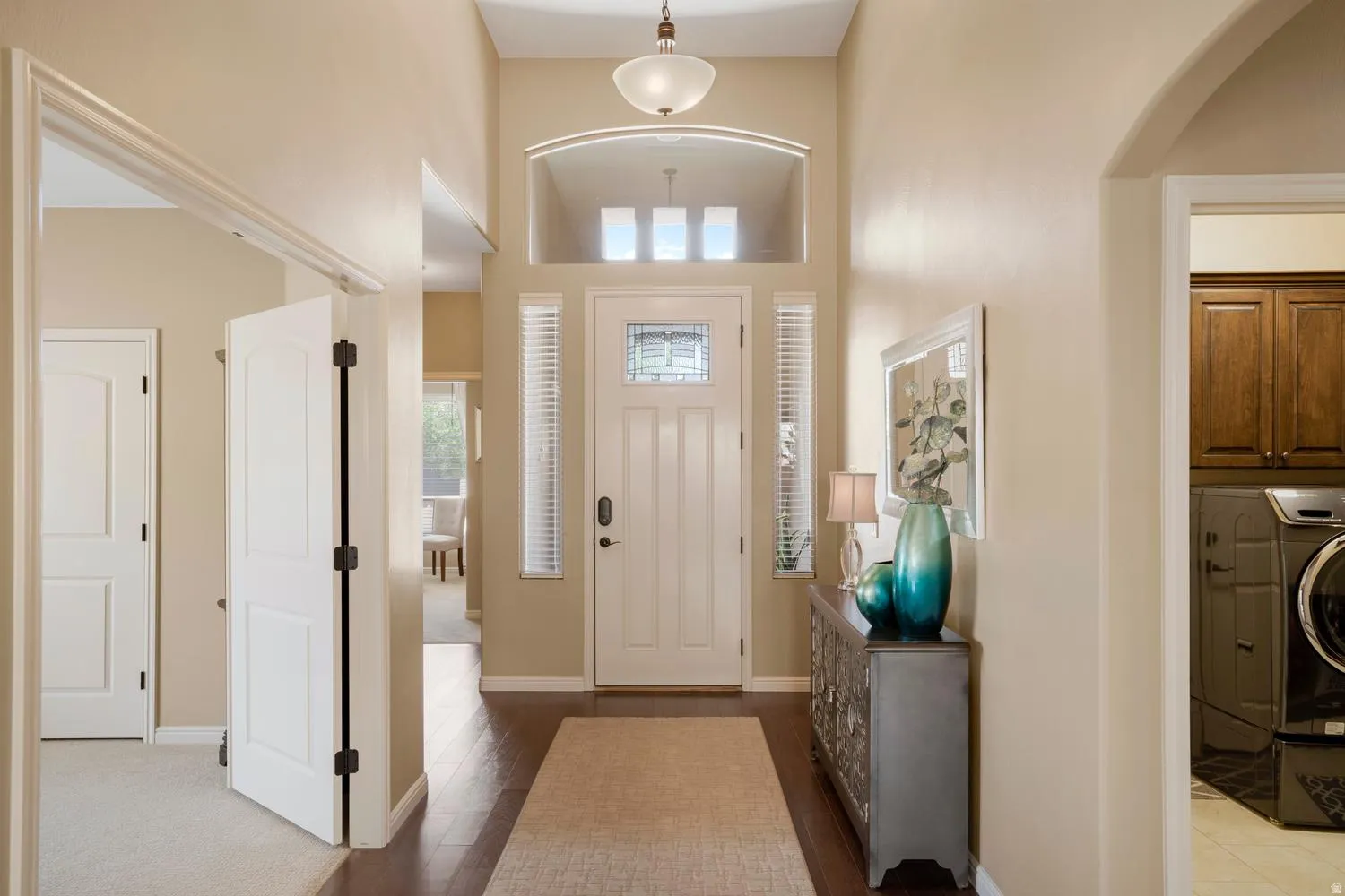 Foyer featuring a high vaulted ceiling, leaded glass front door, transom windows, and wood-finish flooring