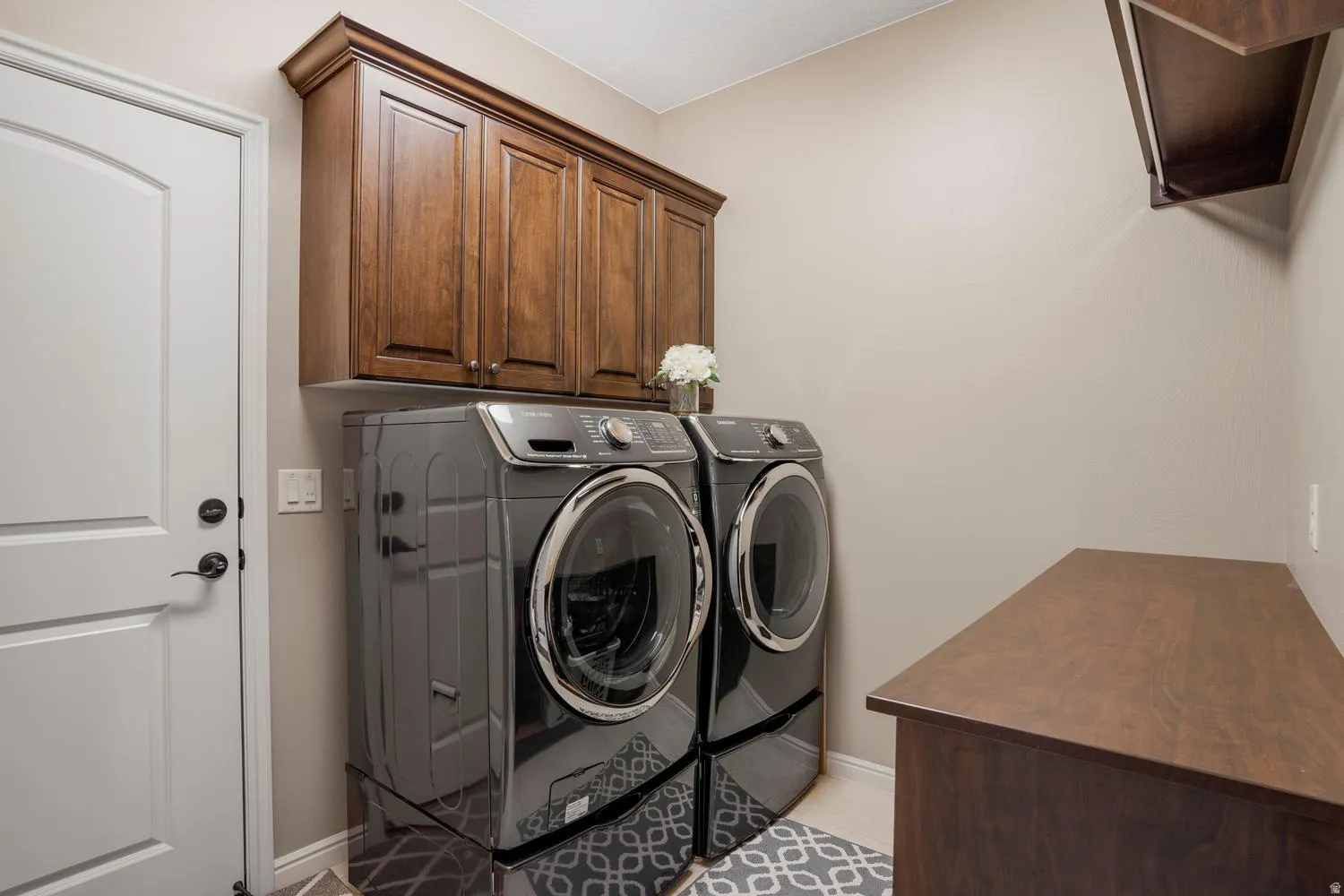 Laundry area featuring dark wood-finish cabinetry, a white panel door with dark hardware, and a built-in wood-finish countertop