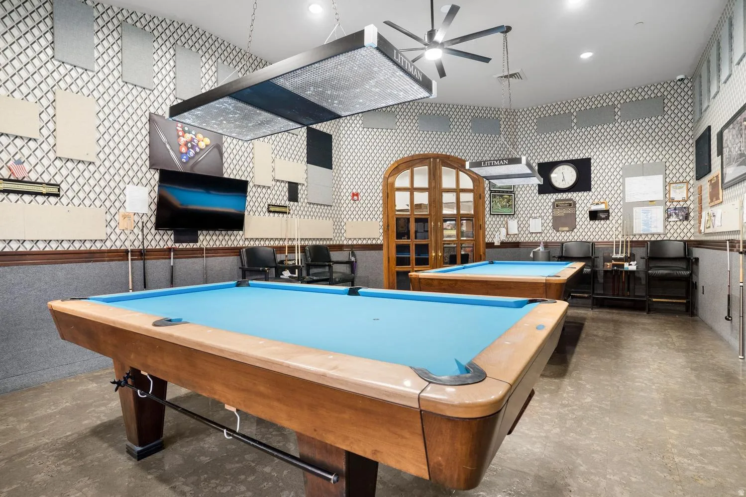 Recreation room with two billiard tables, patterned wallpaper, ceiling-mounted light fixtures, and a ceiling fan