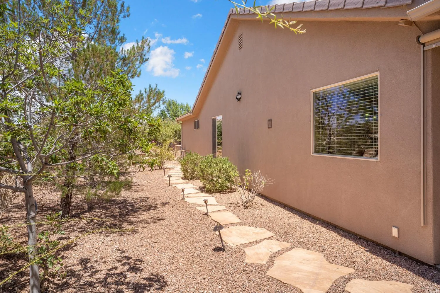 Stucco exterior with a tiled roof, featuring a stone path, ground lighting, and established landscaping