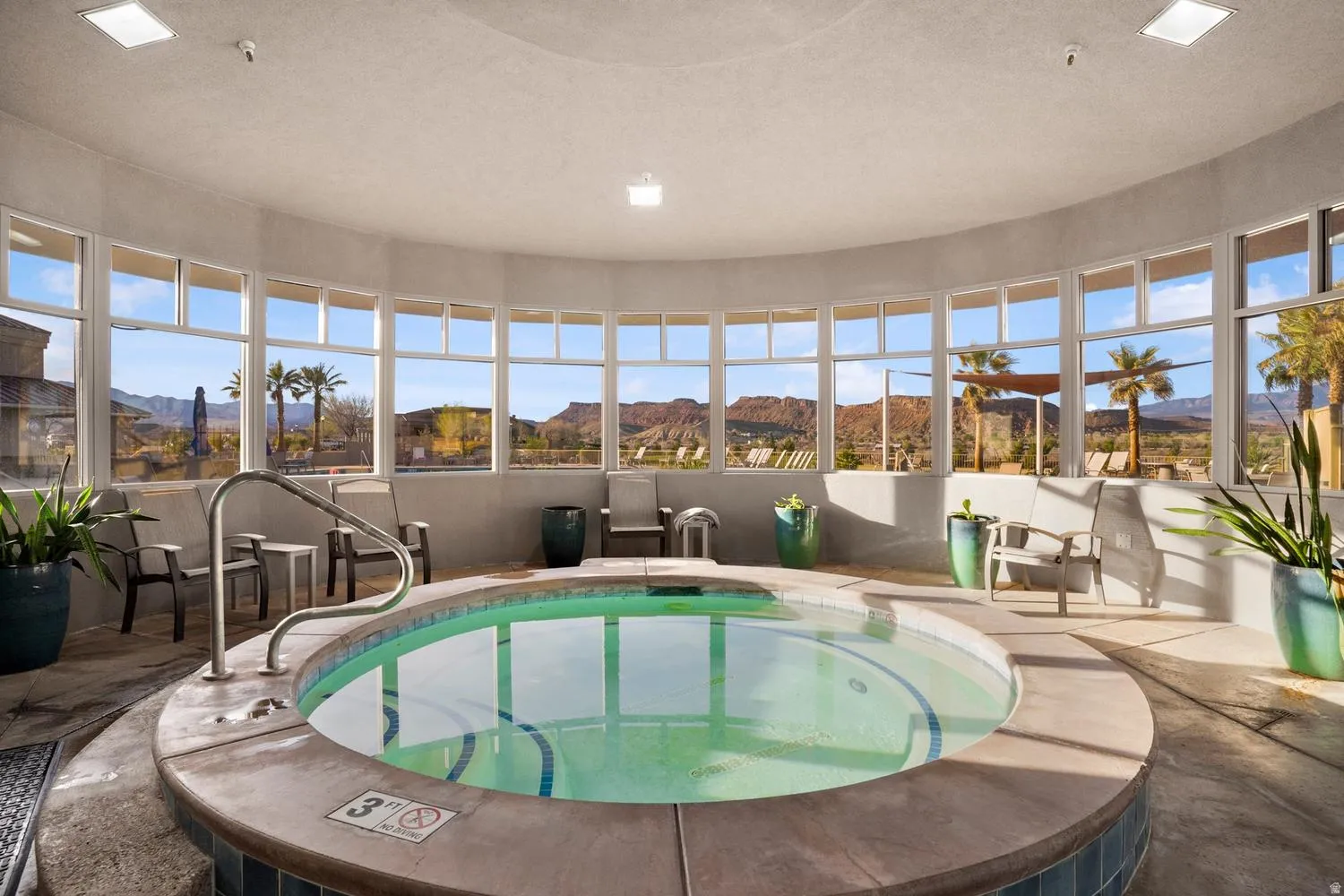 Circular indoor spa with surrounding windows, concrete deck, and recessed lighting