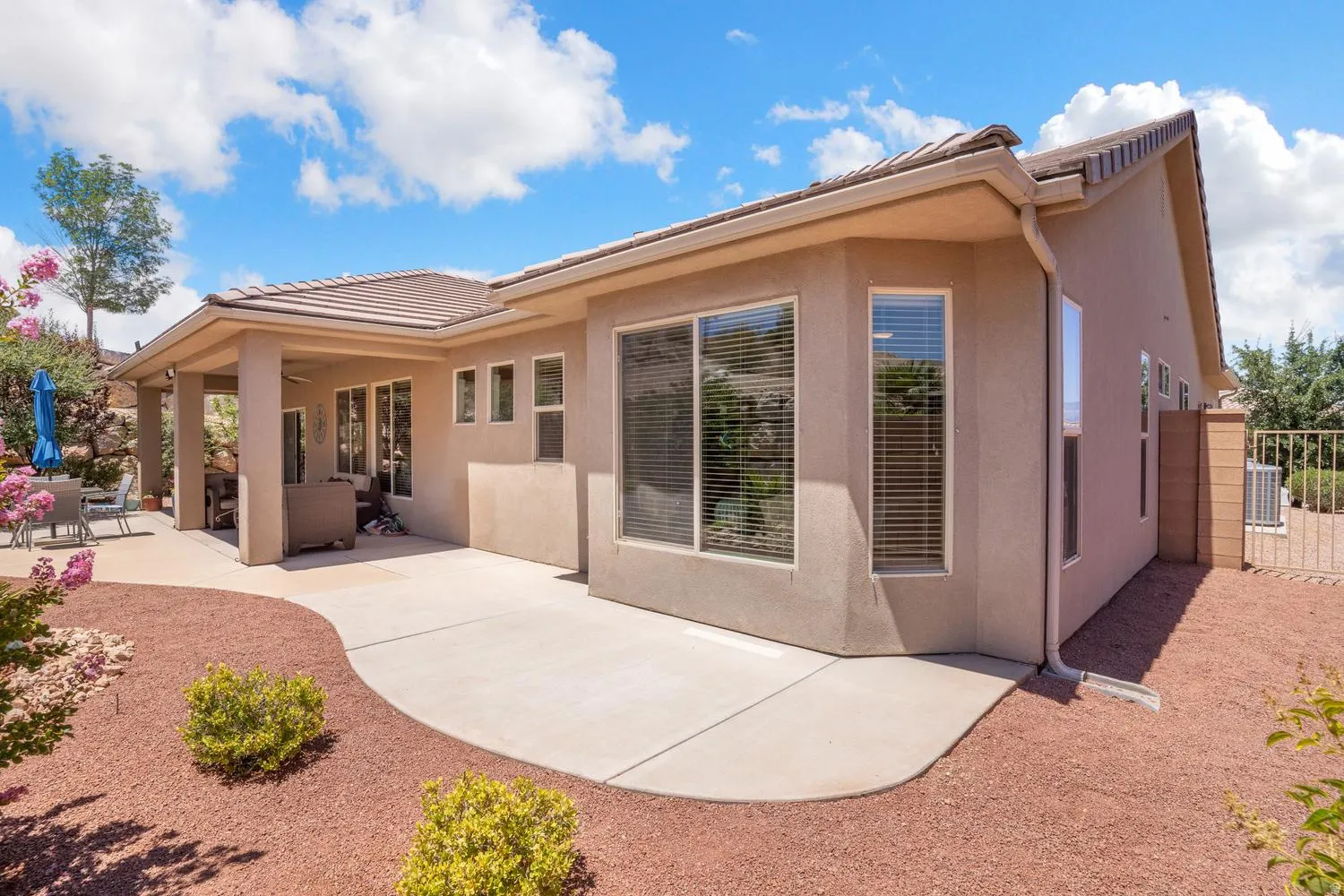 Stucco exterior with a covered patio and concrete hardscaping