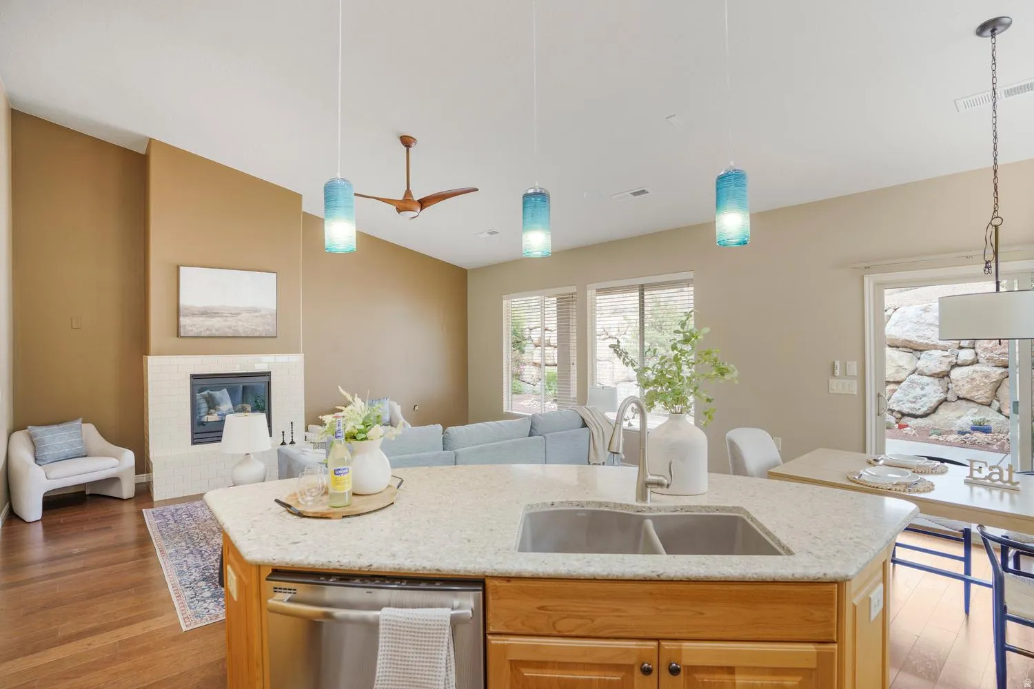 Kitchen island with a double basin sink, granite countertop, and light wood cabinetry