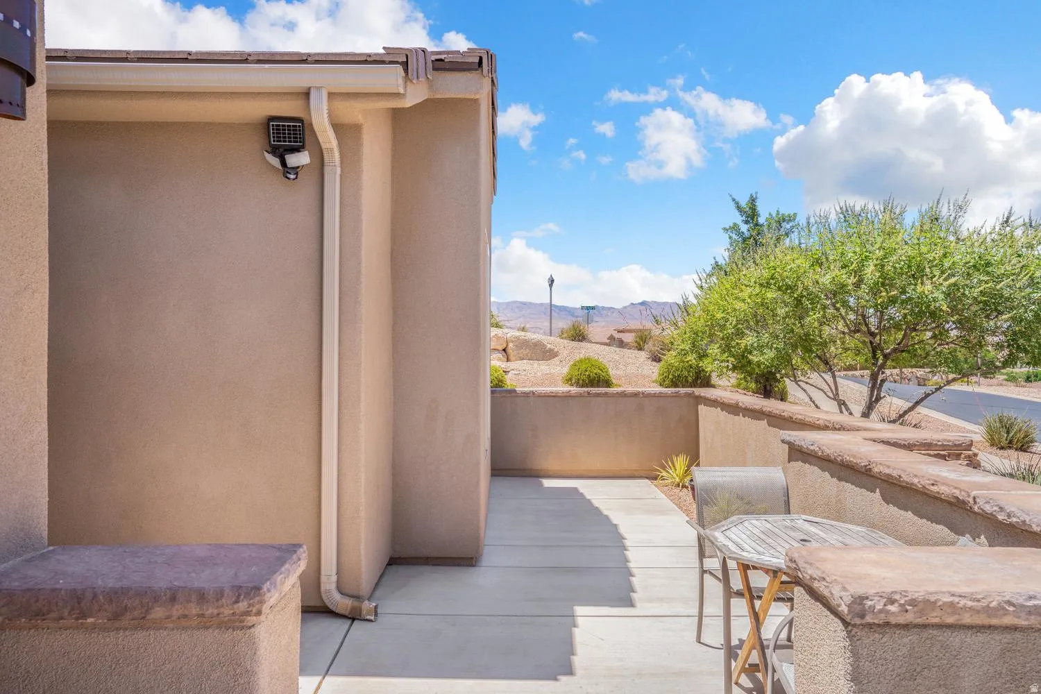 Stucco exterior with a terracotta roof, concrete patio, and stone-capped retaining walls