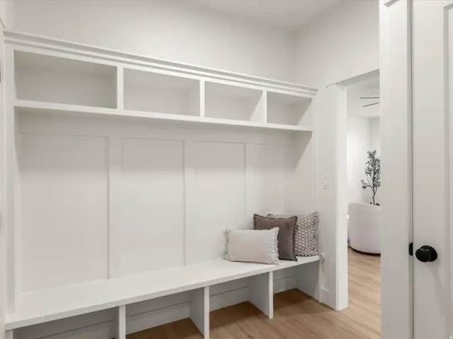 Built-in mudroom bench with open shelving, board and batten wall detailing, and wood-finish flooring