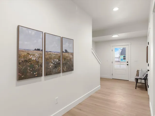 Bright entryway featuring wood-finish flooring, recessed lighting, and a white paneled door with a frosted glass insert