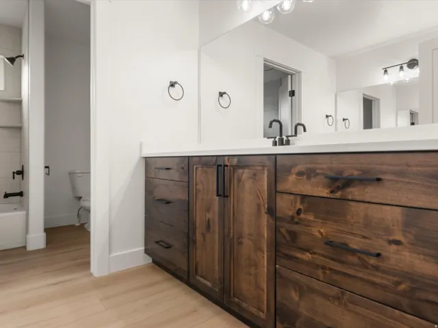 Double vanity with wood-finish cabinetry, white countertop, and dual matte black faucets