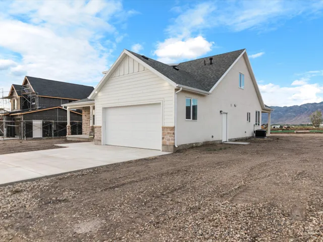 Exterior featuring light-colored siding, a two-car garage, and a concrete driveway