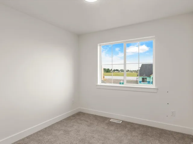 Bright interior space featuring a large window with white trim, gray carpet flooring, white painted walls, and a recessed ceiling light