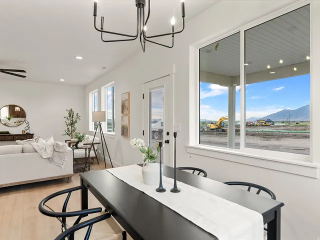 Bright dining area featuring a modern chandelier, light wood-finish flooring, and white walls
