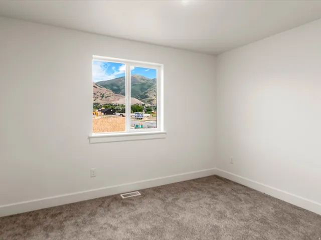 Room with a large window framing a mountain and valley backdrop