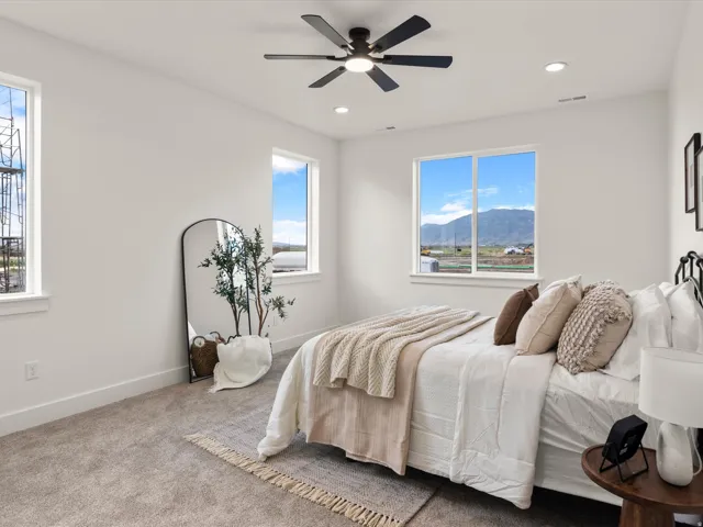 Bright bedroom featuring a ceiling fan with integrated lighting, recessed lighting, and multiple windows