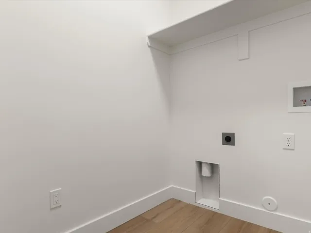 Utility space featuring wood-finish flooring, white baseboards, and a white wall finish
