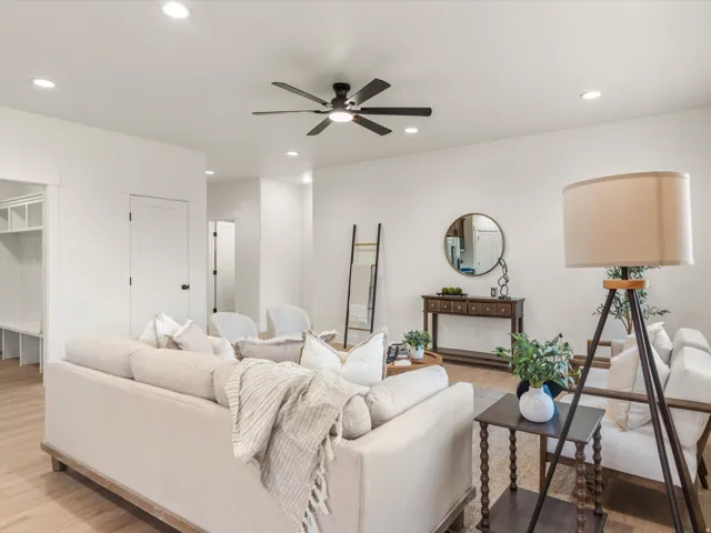 Open-concept living area featuring light wood-finish flooring, a contemporary ceiling fan with integrated lighting, recessed overhead lighting, and white trim throughout