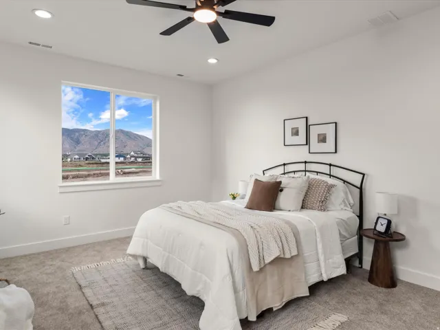 Spacious bedroom featuring a large window, mountain backdrop, recessed lighting, and a ceiling fan