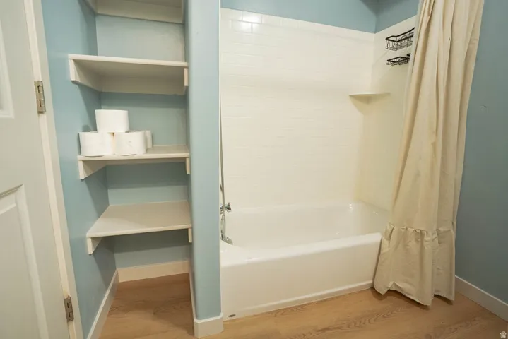 Bathroom featuring a white bathtub, tiled shower surround, and built-in shelving