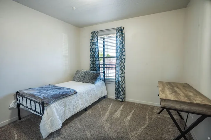 Carpeted room featuring a window with blinds, white walls, and a recessed ceiling light fixture