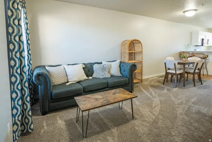Open-concept living space featuring neutral-toned carpeting and light wall paint