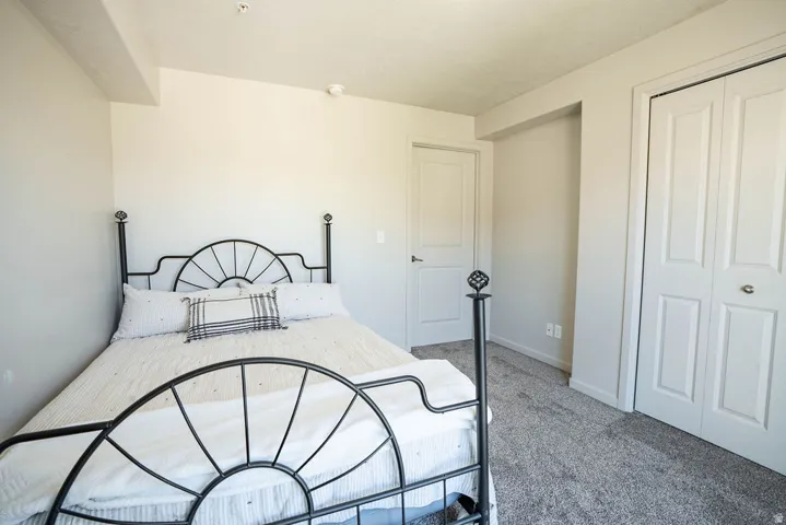 Carpeted bedroom with a double bi-fold closet door and white trim