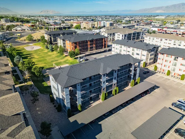 Multi-story residential building featuring balconies, dark gray roof, and light blue siding